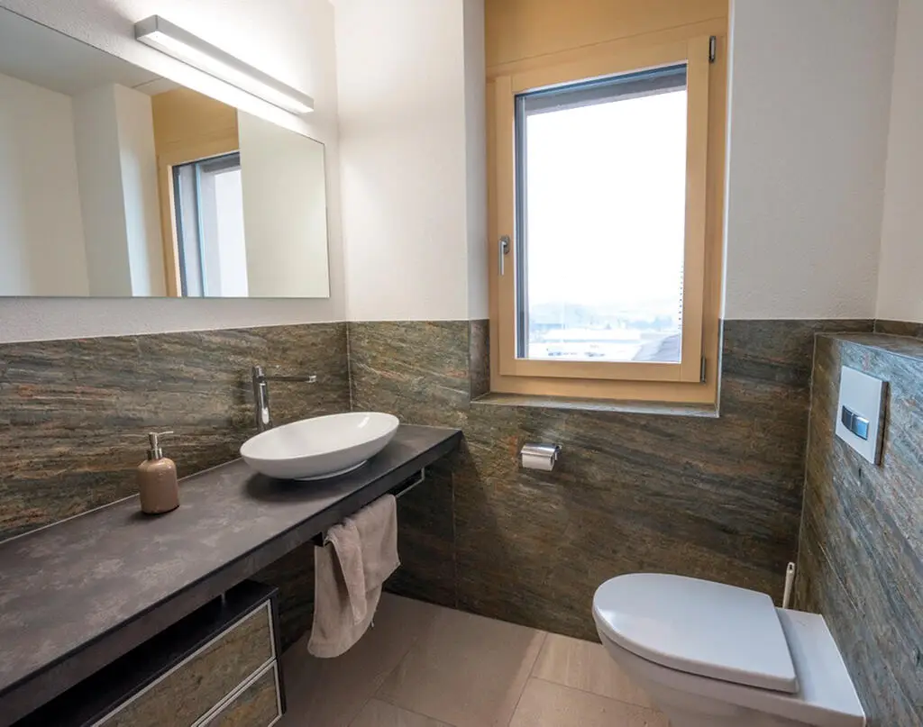 Clean contemporary bathroom with a pale natural stone wall, floating vanity, and soft lighting